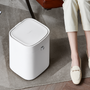 Trash King Royal Bin smart trash can placed beside a modern chair in a stylish living room, highlighting its sleek, touchless design for minimal home aesthetics.