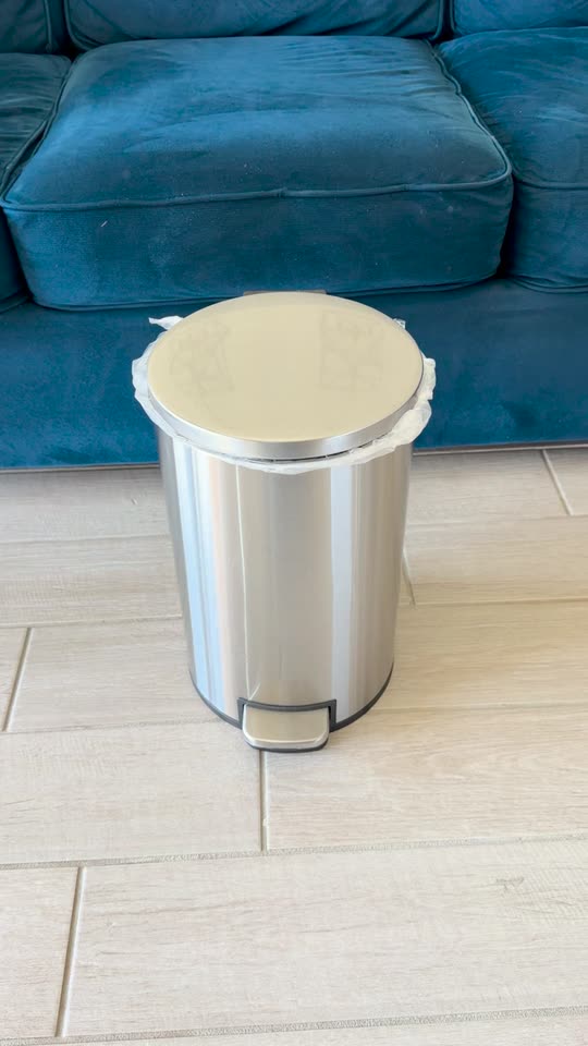A stainless steel pedal bin by a sofa, then the Royal Bin® NOIR 17L in the same spot